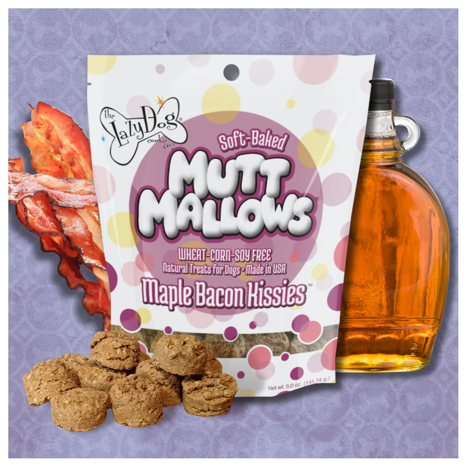 Bag of Maple Bacon Kissies Mutt Mallows standing upright on a textured background, surrounded by bacon slices, a glass bottle of maple syrup, and several round brown dog treats in front.