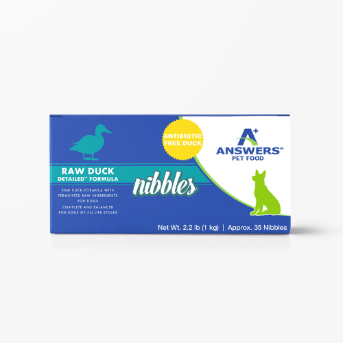 Front view of a blue Answers Pet Food box labeled “Raw Duck Detailed Formula nibbles,” featuring a duck icon, an “Antibiotic Free Duck” badge, and text indicating raw duck with fermented raw ingredients, complete and balanced for dogs of all life stages, with net weight 2.2 lb and approximately 35 nibbles.