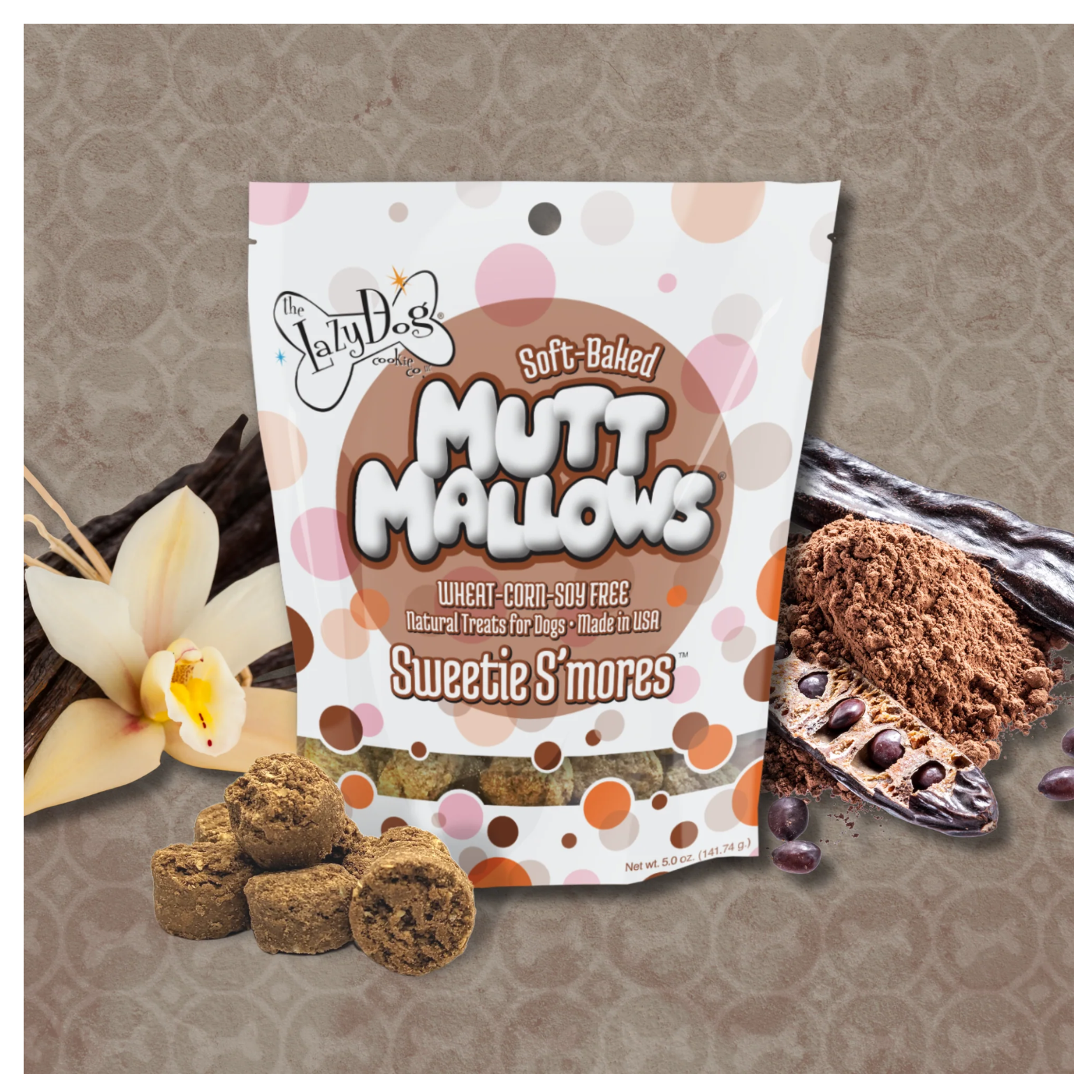 Sweetie S’mores Mutt Mallows bag standing on a neutral background, surrounded by vanilla pods, cocoa powder, and several brown, round soft-baked dog treats in front.