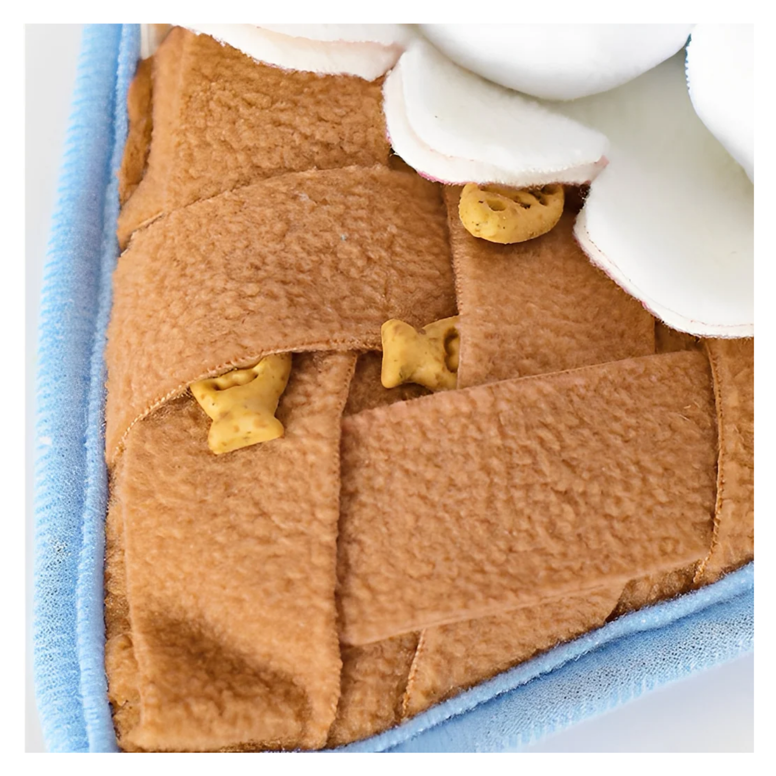 Close-up of the waffle-cone base made of tan textured fabric strips, with small yellow treats hidden between the layers to encourage foraging.